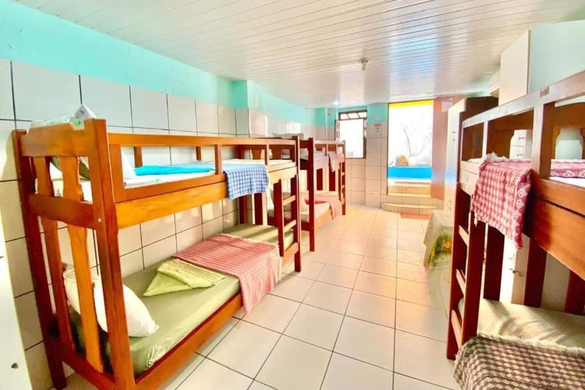 A dormitory room with bunk beds, tiled walls, and a window with a view.