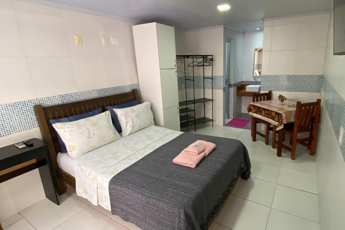 A bedroom with a bed, a desk, and a chair.