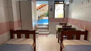 Una habitación con dos camas, una mesita y un ventanal.
