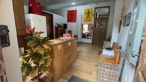 Un mostrador de recepción de madera con una planta, un refrigerador y una puerta con espejo.
