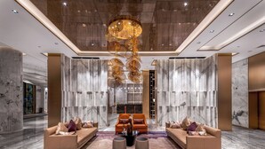 A spacious lobby with a central seating area, marble walls, and a modern chandelier. - Imperial Dragon Bay Purejoy Hotel (Nanning)