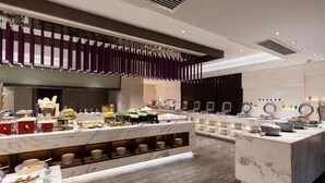 A modern hotel lobby with marble counters, a central seating area, and a decorative hanging element. - Imperial Dragon Bay Purejoy Hotel (Nanning)
