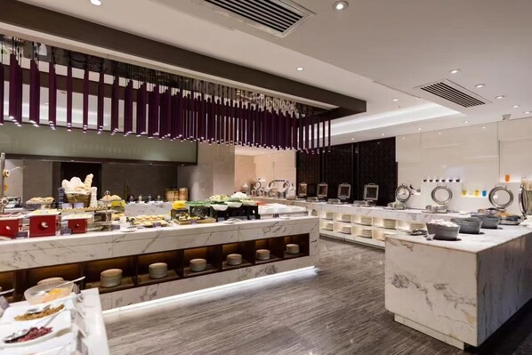 A modern hotel lobby with marble counters, a central seating area, and a decorative hanging element. - Imperial Dragon Bay Purejoy Hotel (Nanning)