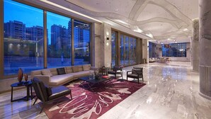 A spacious lobby with a large seating area, a coffee table, and a view of tall buildings outside. - Imperial Dragon Bay Purejoy Hotel (Nanning)