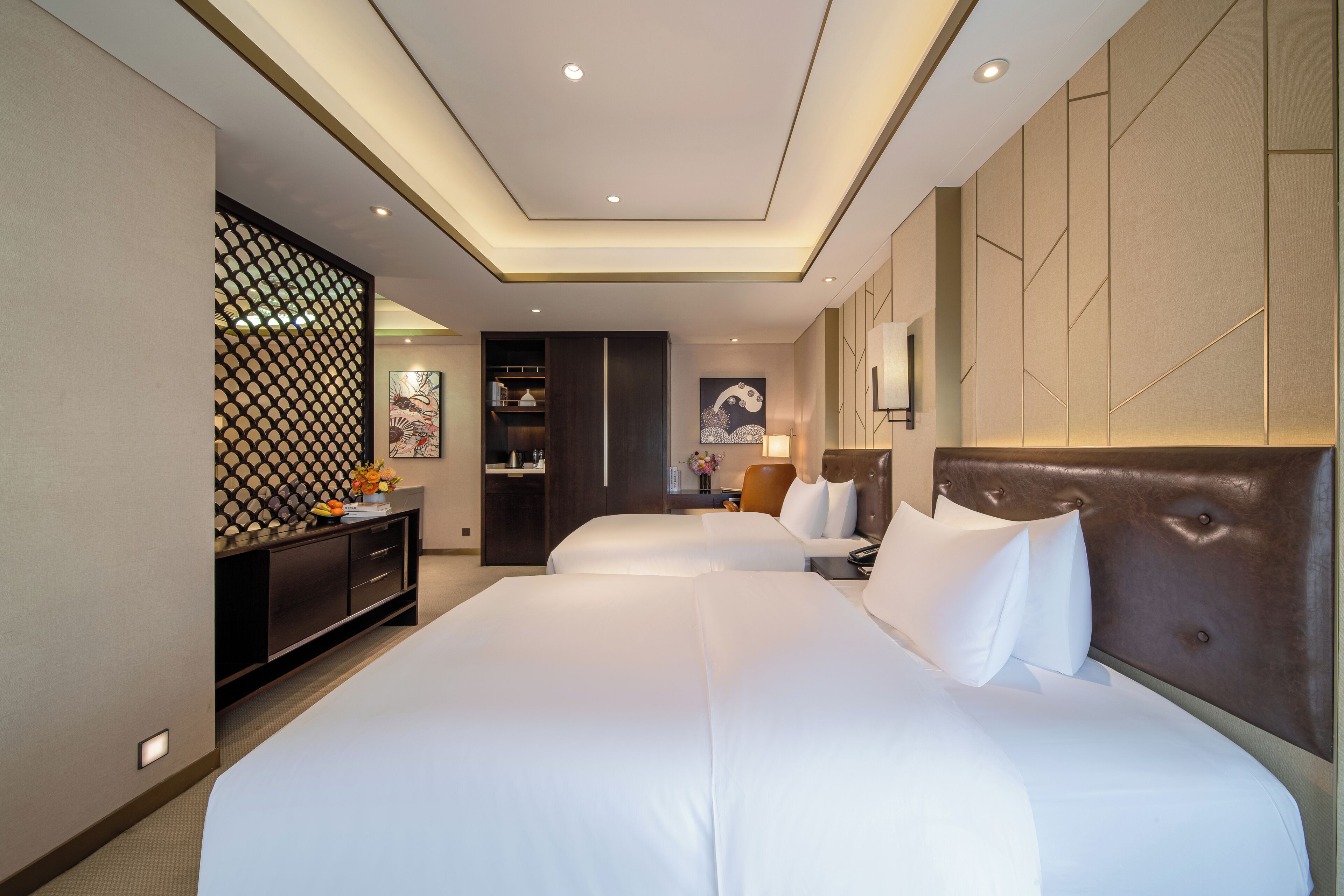 A hotel room with a large bed, a desk, a cabinet, and a decorative wall panel.