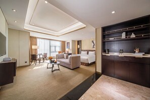 A modern hotel room with a large bed, a sofa, a dining area, and a kitchen counter. - Imperial Dragon Bay Purejoy Hotel (Nanning)