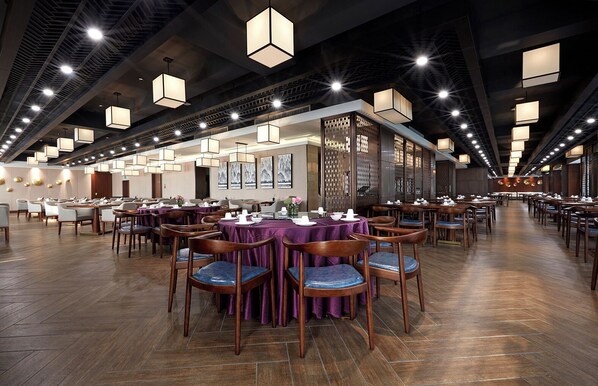 Un vaste espace dédié à la salle à manger, avec de nombreuses tables et chaises, un plafond haut agrémenté de luminaires suspendus et un aménagement intérieur moderne.