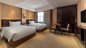 Une chambre d’hôtel avec deux lits, un bureau, une chaise, une télévision et une grande fenêtre avec des rideaux.