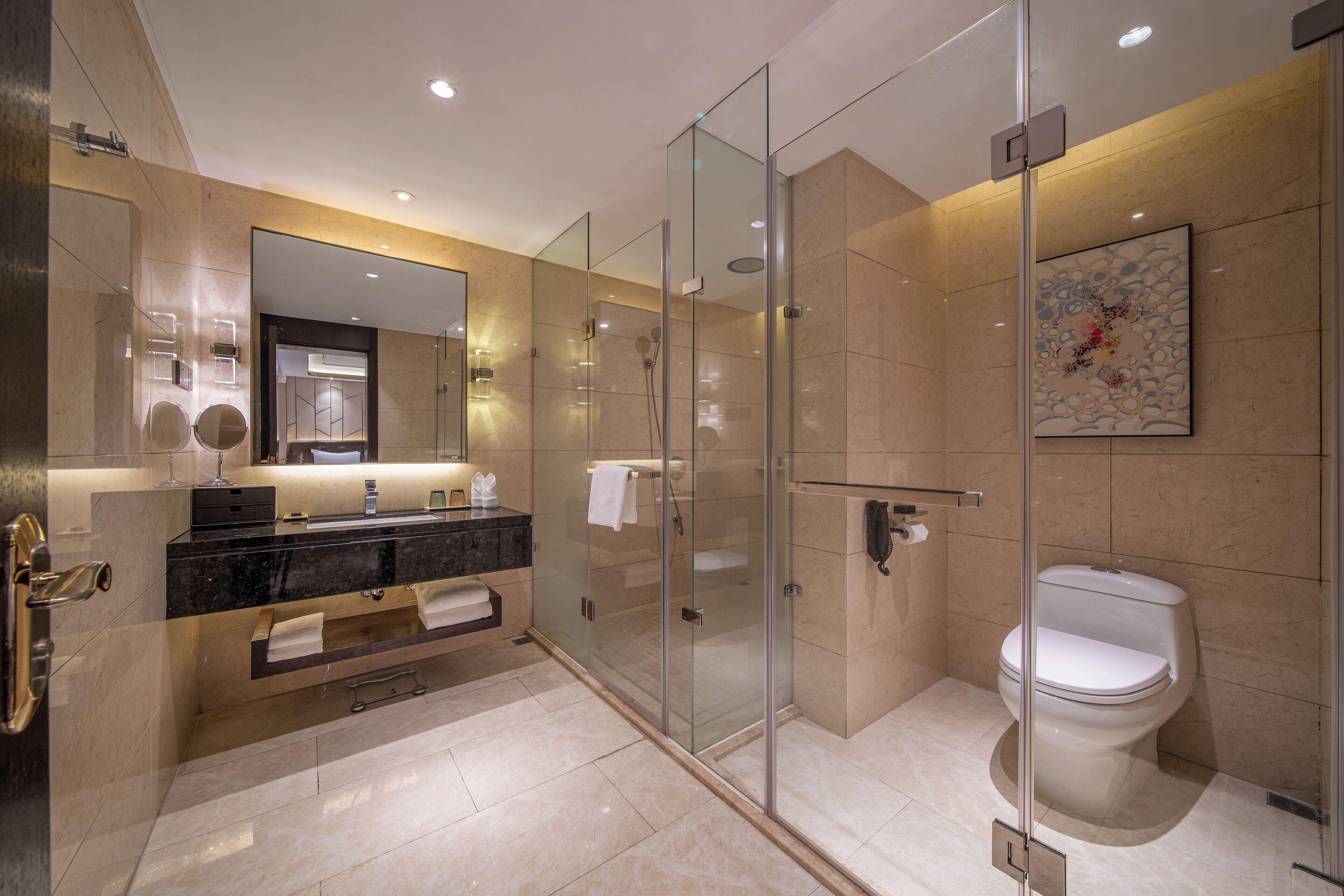 A modern bathroom with a glass-enclosed shower, a white toilet, and a black marble sink.
