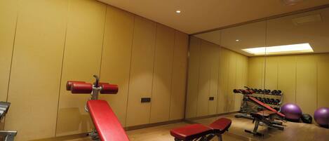 A gym with benches, dumbbells, and exercise balls.