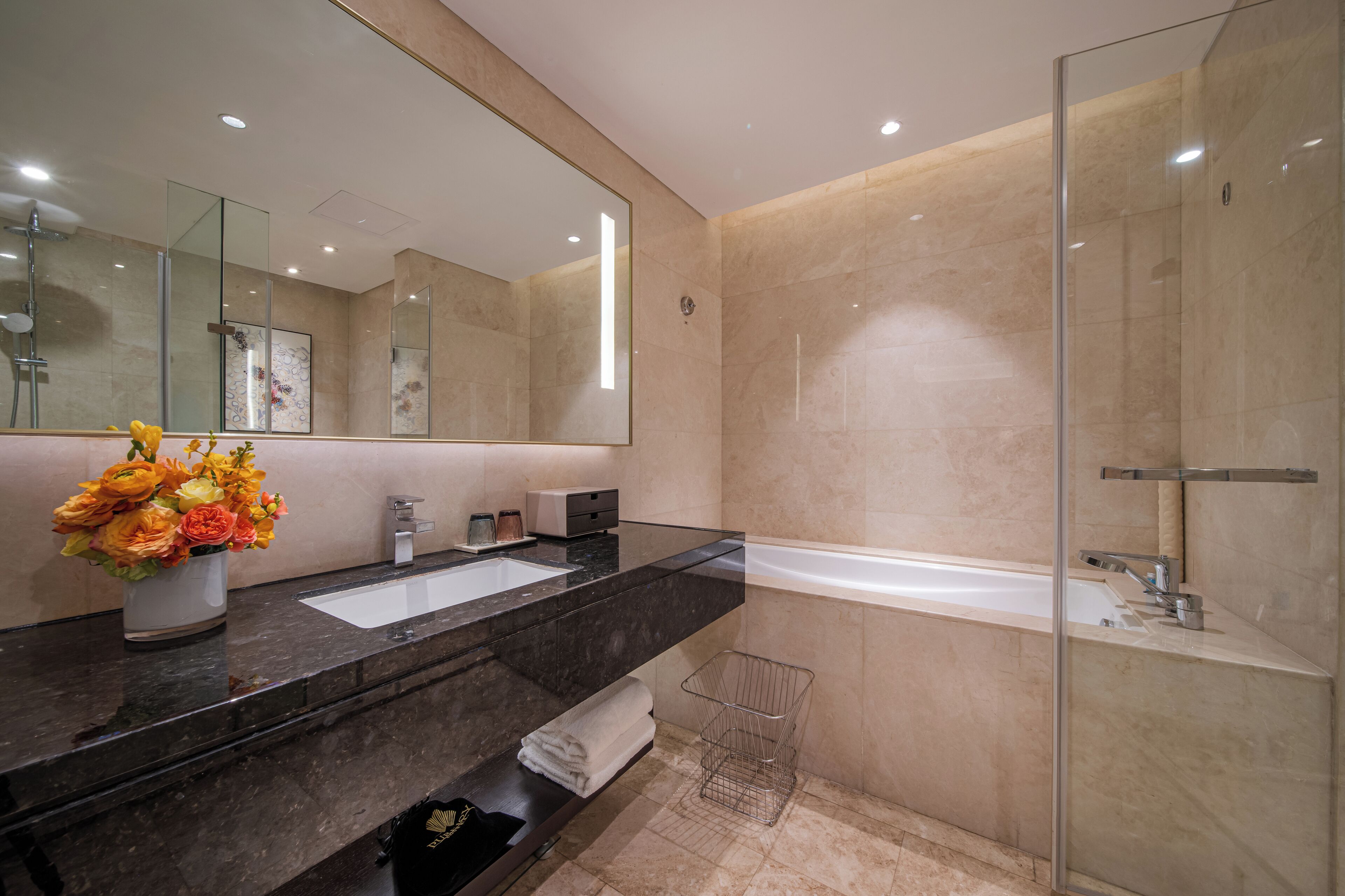 A modern bathroom with a large mirror, a bathtub, and a shower.