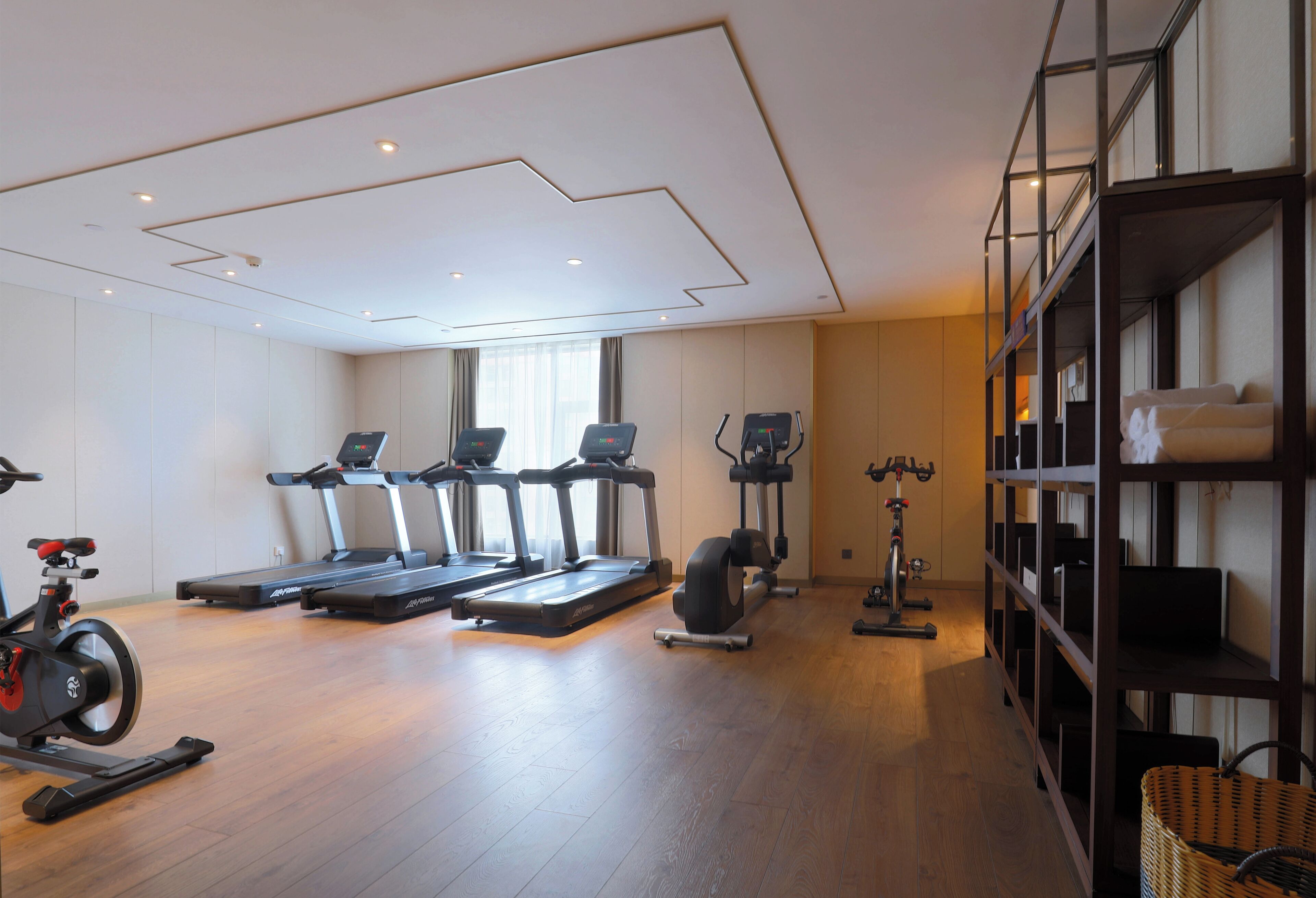 A modern gym with treadmills, stationary bikes, and a rowing machine.