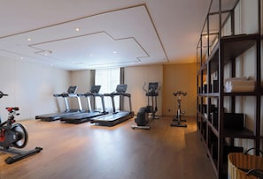 A modern gym with treadmills, stationary bikes, and a rowing machine.