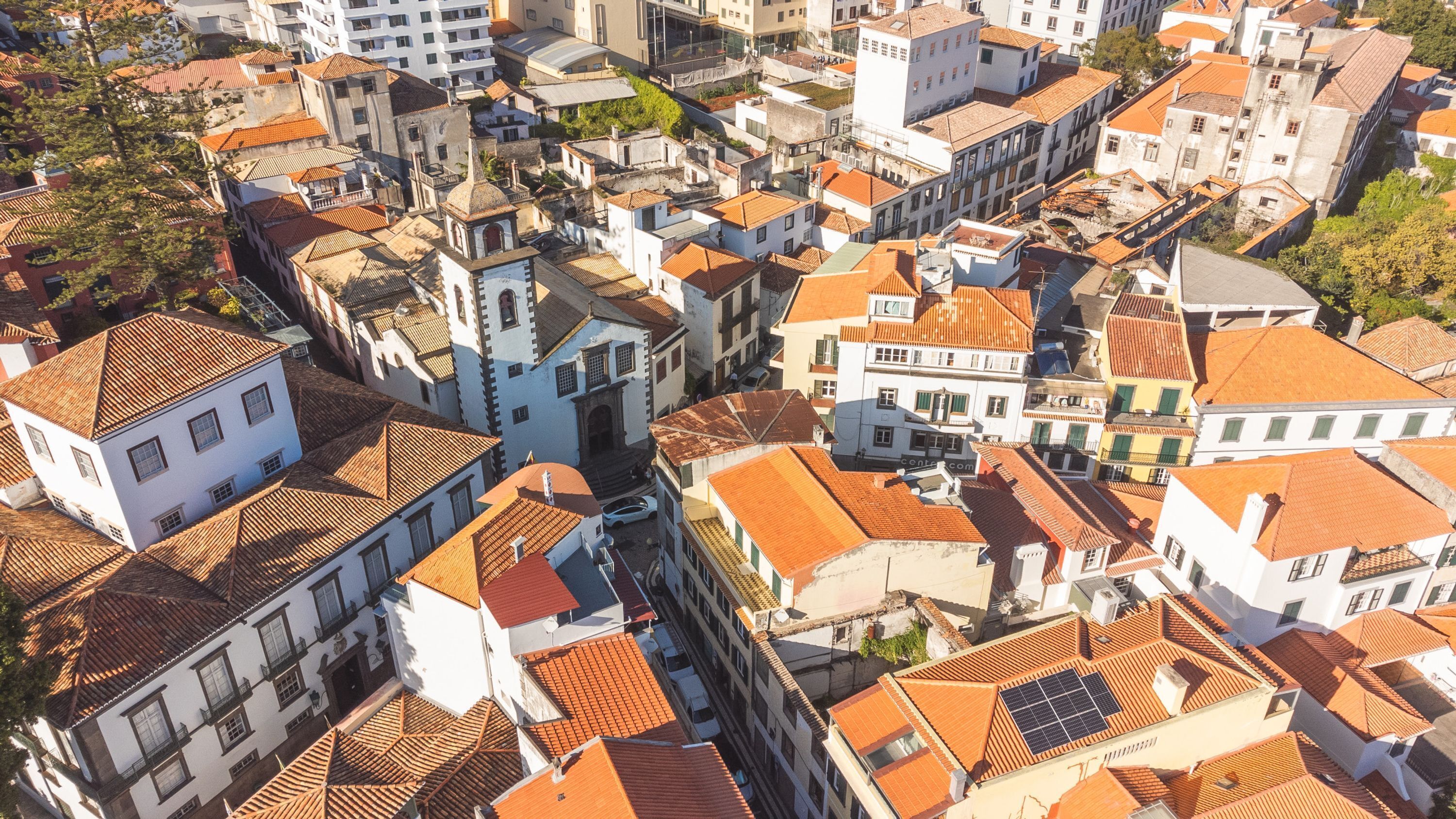 Vista aérea de uma área urbana densamente povoada, com edifícios multifamiliares construídos próximos uns dos outros, apresentando uma variedade de estilos arquitetônicos e uma mistura de estruturas residenciais e comerciais.
