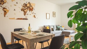 A dining area with a world map mural, a dining table set with plates and glasses, and a grey sofa in the background.