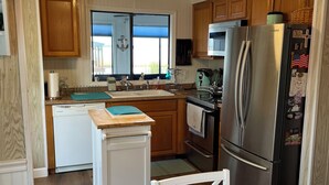 Una cocina con armarios de madera, un refrigerador de acero inoxidable, un microondas y un lavamanos.