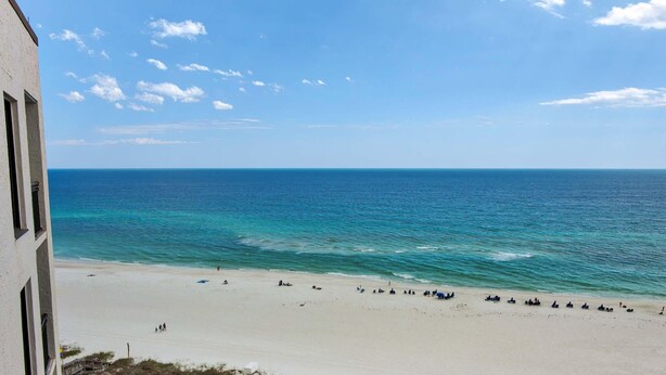 Ein Strand mit blauem Himmel, sandigem Ufer und einem Gebäude links.