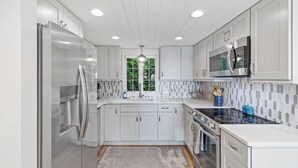 Et moderne køkken med hvide skabe, rustfrie stål hvidevarer og et backsplash med et fisbenmønster.