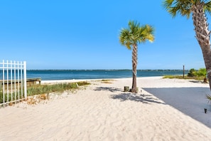 A sandy beach with a palm tree, a white fence, and a clear blue sky. - Southern Charm (Navarre)