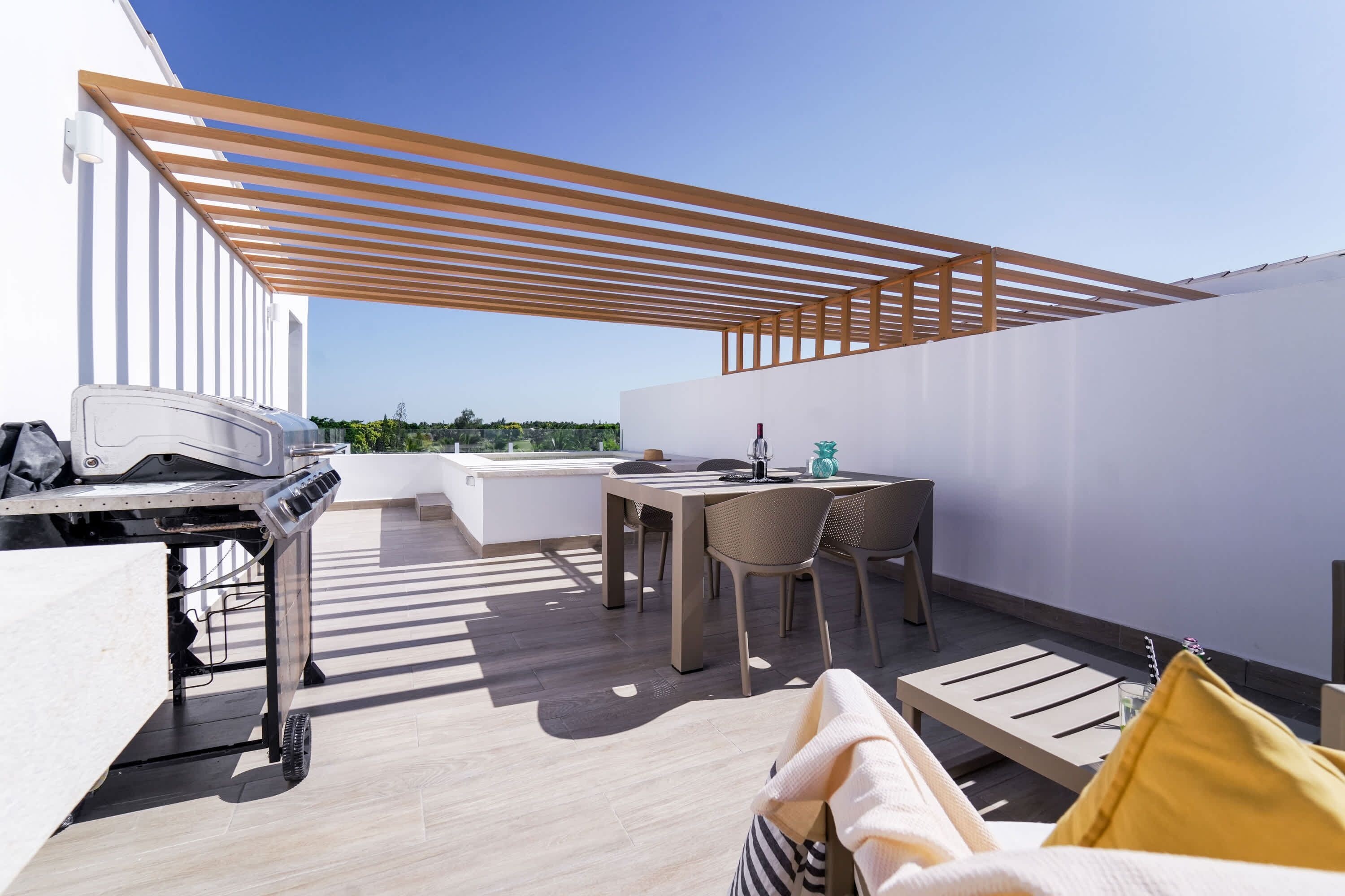 En takterrass med ett matområde, en grill och sittplatser.