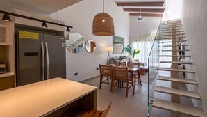 A modern kitchen with a built-in refrigerator, a dining area with a table and chairs, and a staircase with glass railings. - Exclusive Penthouse With Picuzzi Steps From Beach (Punta Cana)