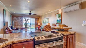 A modern kitchen with granite countertops, a built-in oven, and a dining area with a round table and chairs. - Oceanfront Seaside Sanctuary Stunning Views w 2 Lanais Whales Watching Haven (Lahaina)