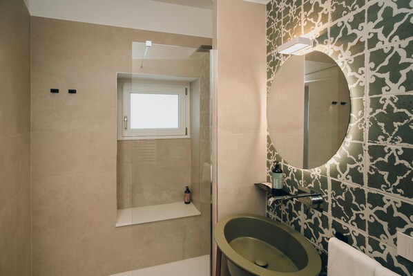 A modern bathroom with a large oval sink, a mirror, and a shower enclosure.