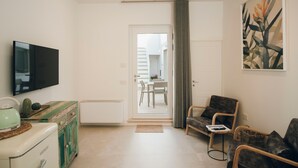 A living room with a flat-screen TV, a vintage refrigerator, a dining area with a table and chairs, and a large window with curtains. - Suite 13 B - San Lorenzo Suites (Putignano)