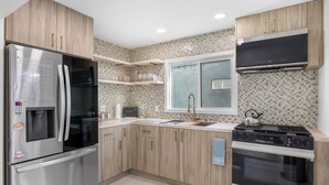 A modern kitchen with wooden cabinets, stainless steel appliances, and a tiled backsplash.