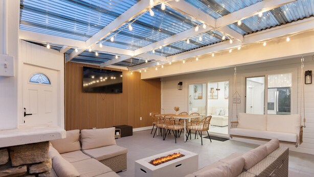 A modern outdoor living area with a fire pit, seating, and a dining set.