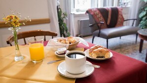 Ein Frühstückstisch für zwei Personen, gedeckt mit Croissants, Orangensaft und einer Tasse Kaffee.