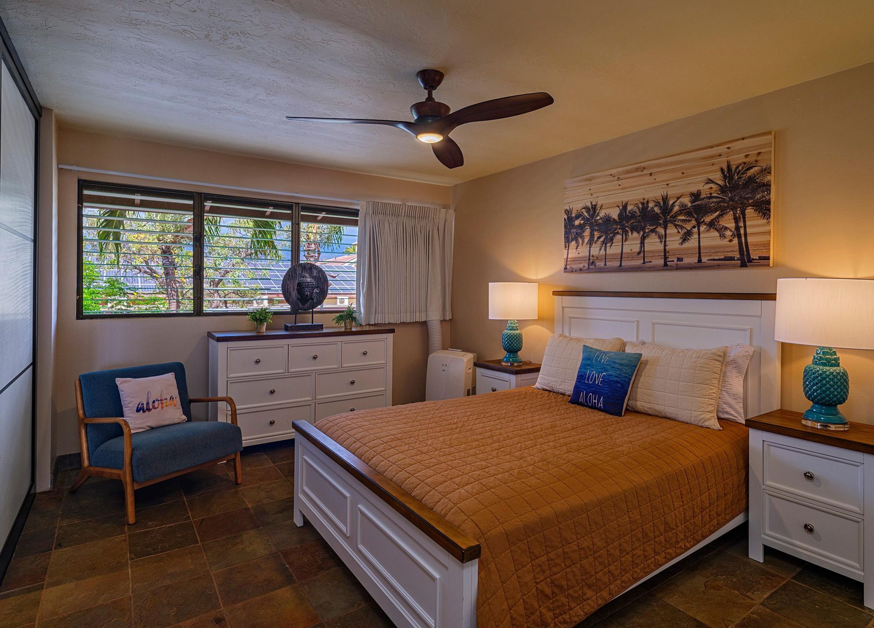 A bedroom with a bed, a chair, a dresser, a nightstand, a ceiling fan, and a window with blinds.