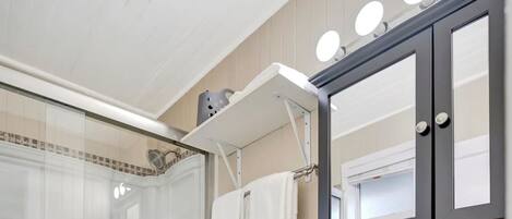 A modern bathroom with a glass-enclosed shower, a white toilet, a vanity with a mirror, and a sink.
