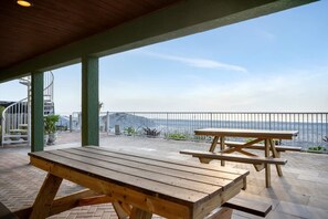 An outdoor patio with picnic tables and a view of the sea. - Stones Throw Beachfront Family Suite 3 Views (Indian Rocks Beach)