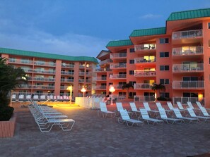 Ein Hotel mit mehreren Balkonen, Außenbereichen zum Sitzen und einem Pool.