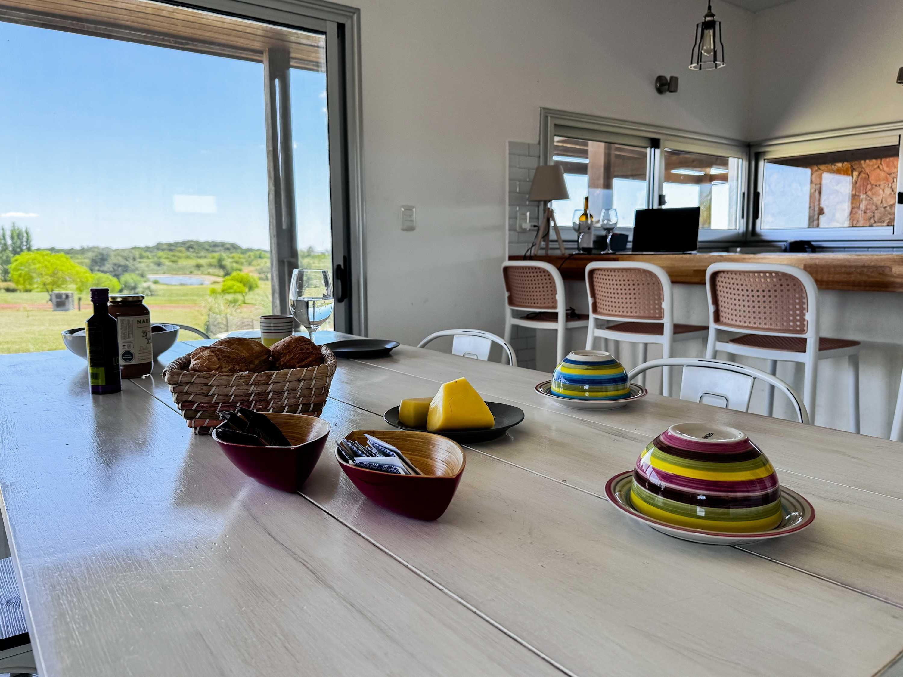 A dining table with a variety of food items and a view of the outdoors.