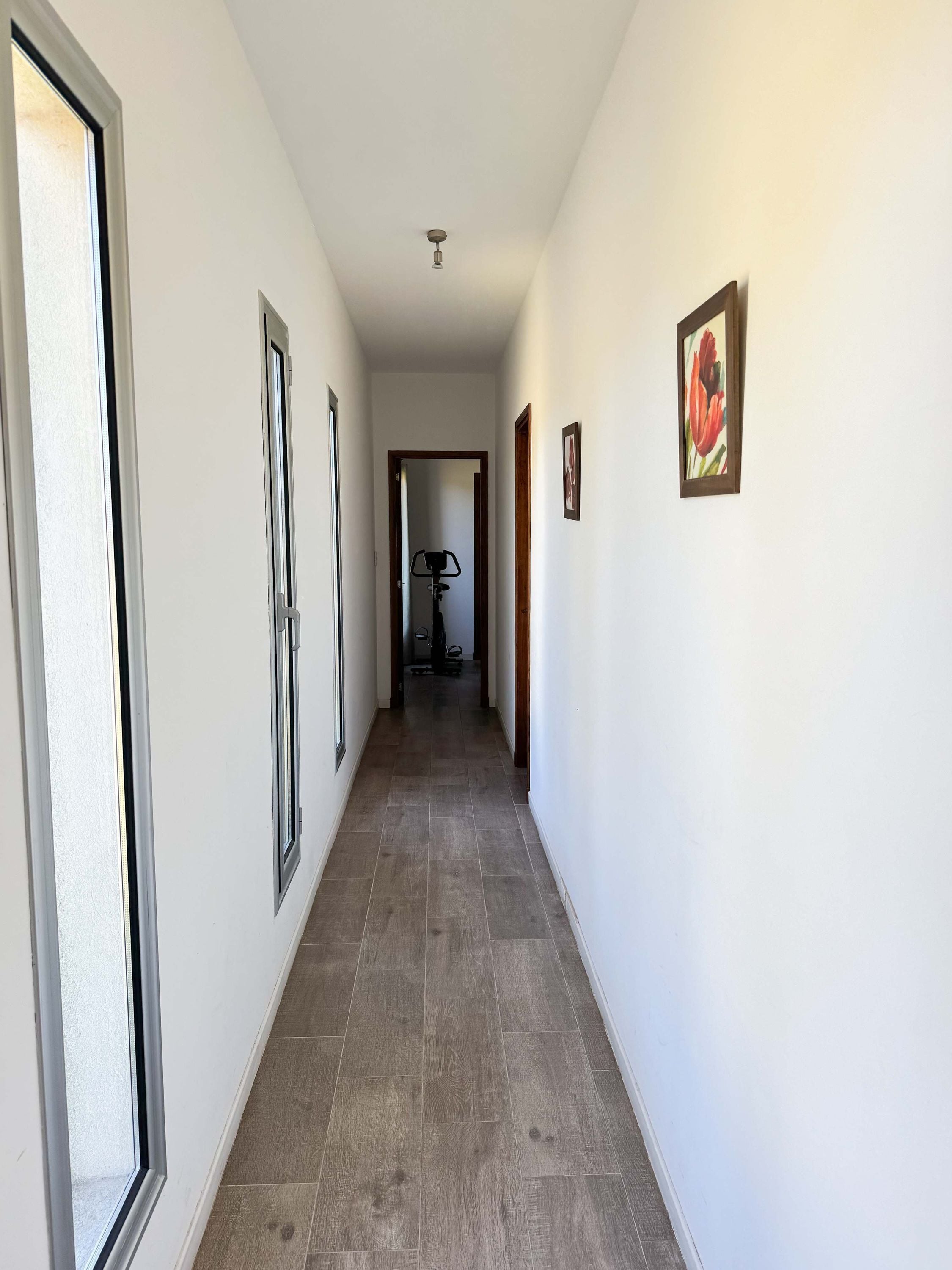 A hallway with white walls, a tiled floor, and a ceiling light.