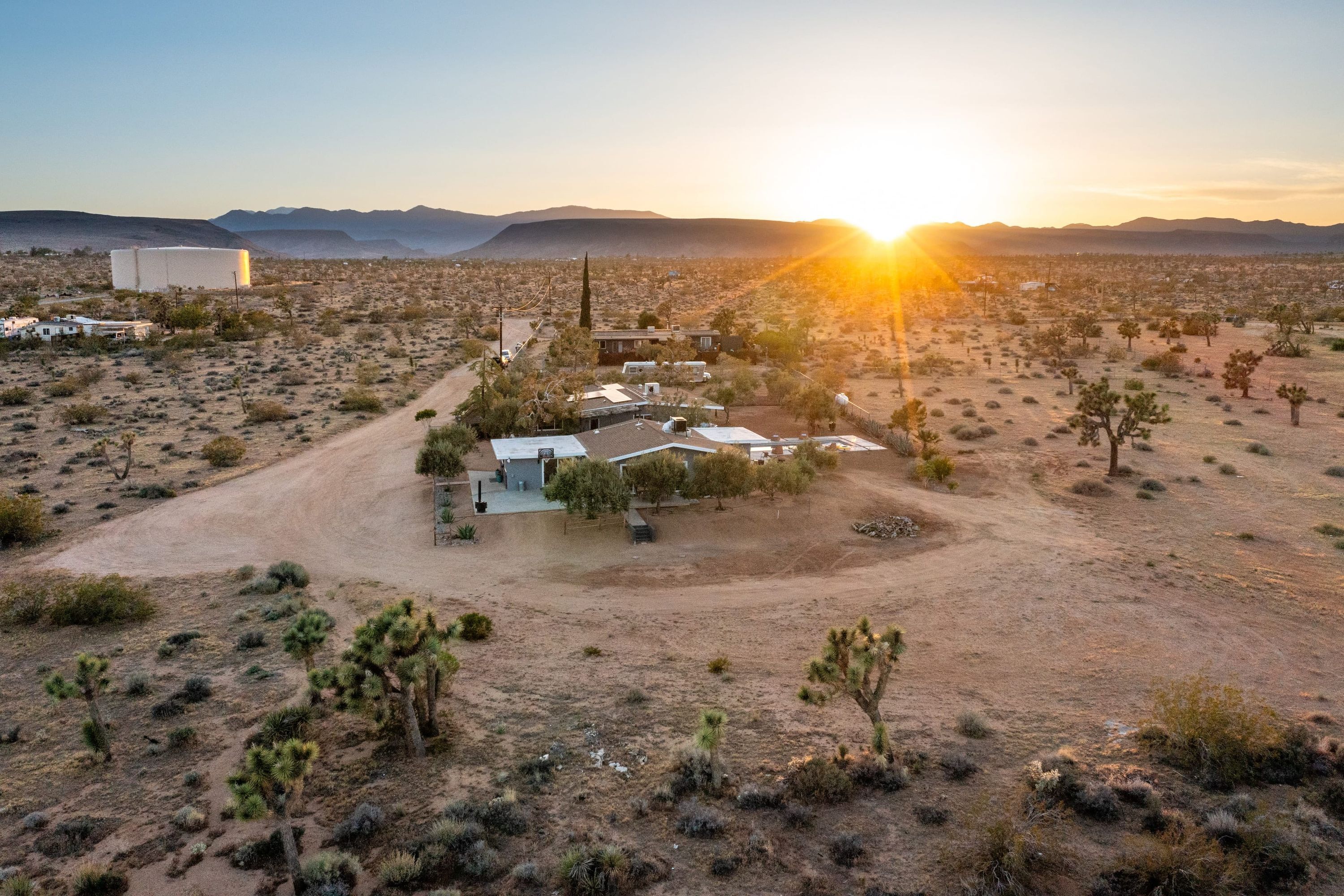 A desert landscape with sparse vegetation and a small cluster of buildings.