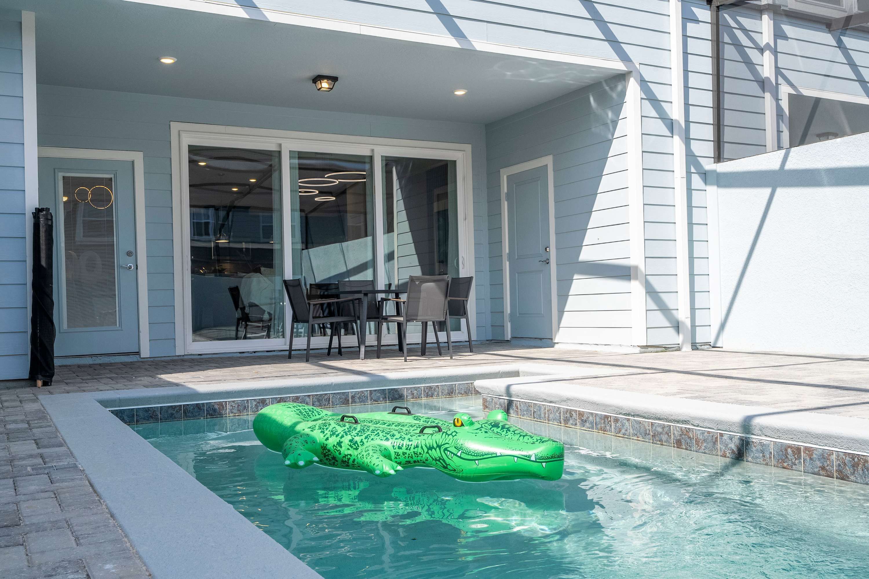 A swimming pool with a green inflatable crocodile float.