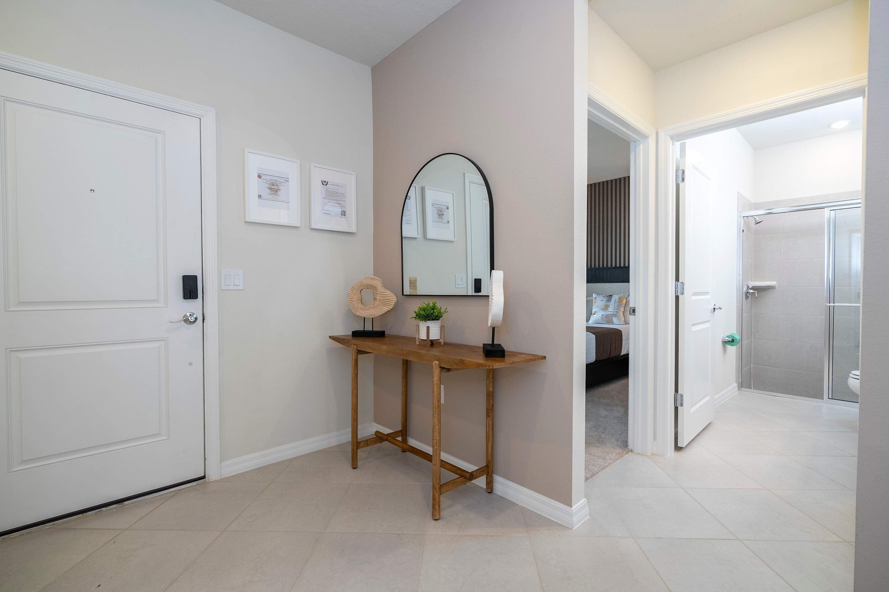 A hallway with a wooden console table, framed certificates, and a large mirror.