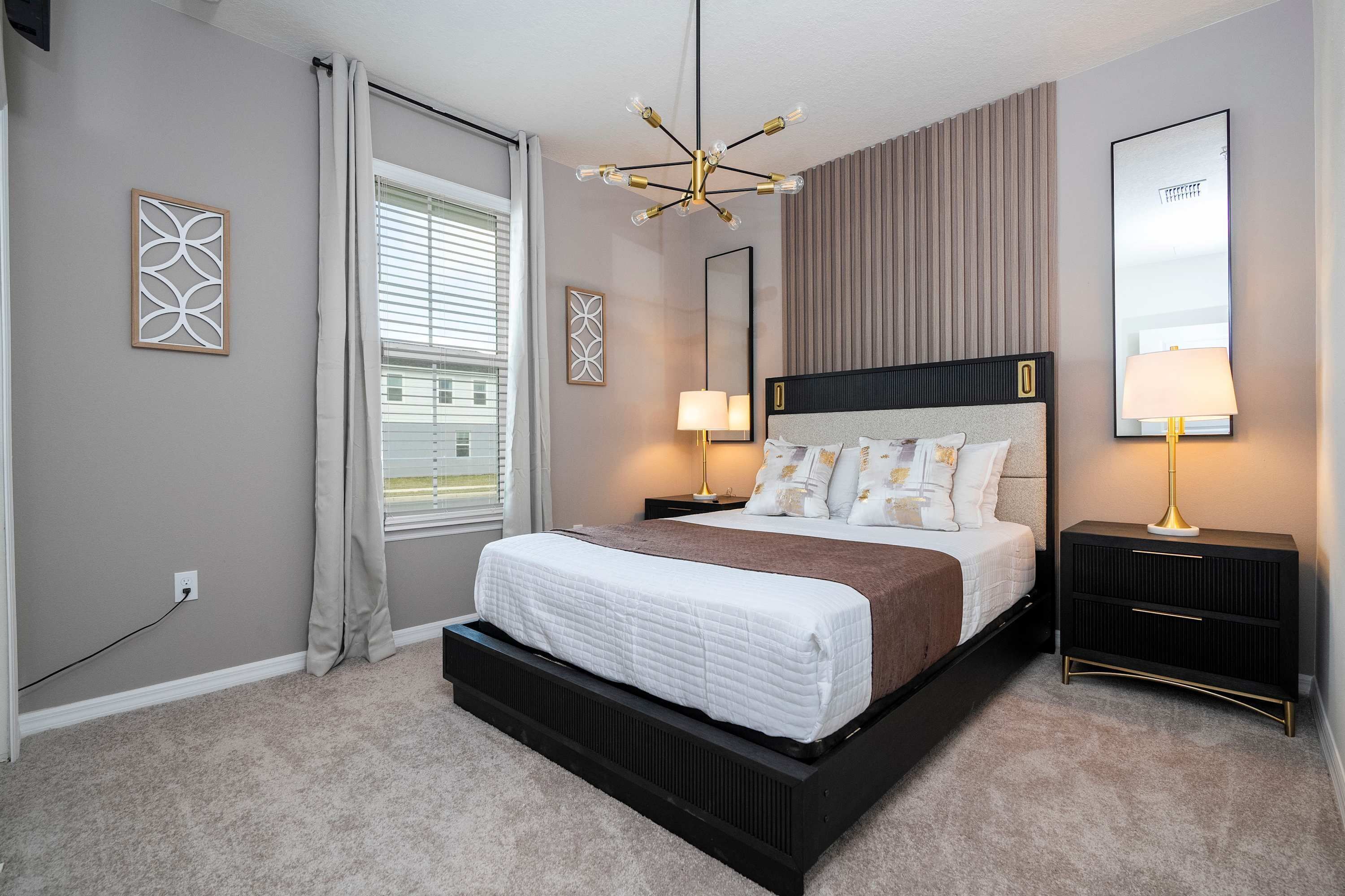 A modern bedroom with a large bed, bedside lamps, a ceiling light, and a window with curtains.