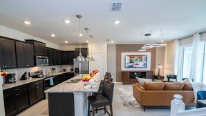 A modern kitchen with dark cabinets, a large island, and stainless steel appliances.