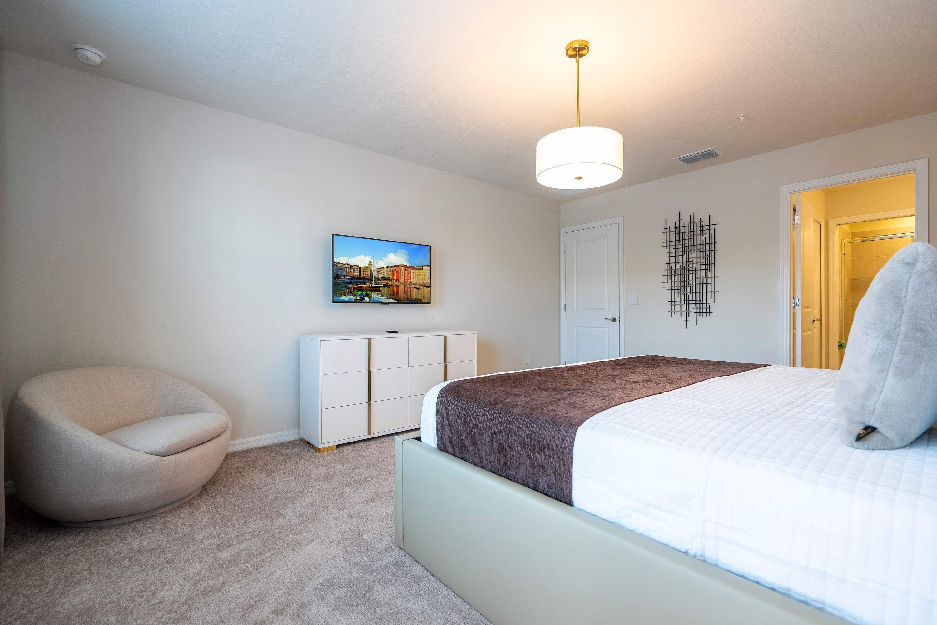 Une chambre à coucher avec un lit, une chaise, une commode et un tableau au mur.