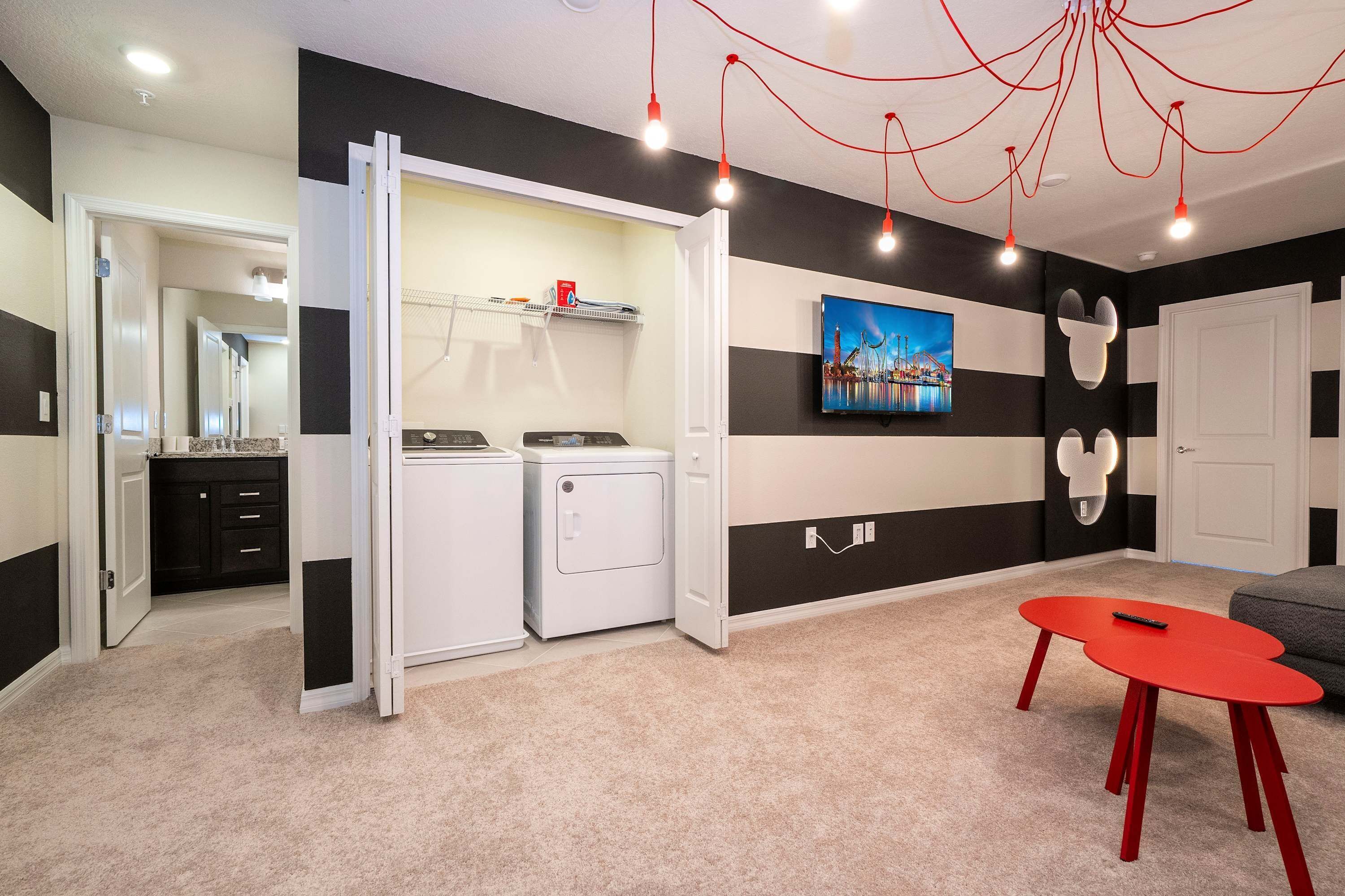 A laundry room with two washing machines, a drying rack, and a wall-mounted TV.
