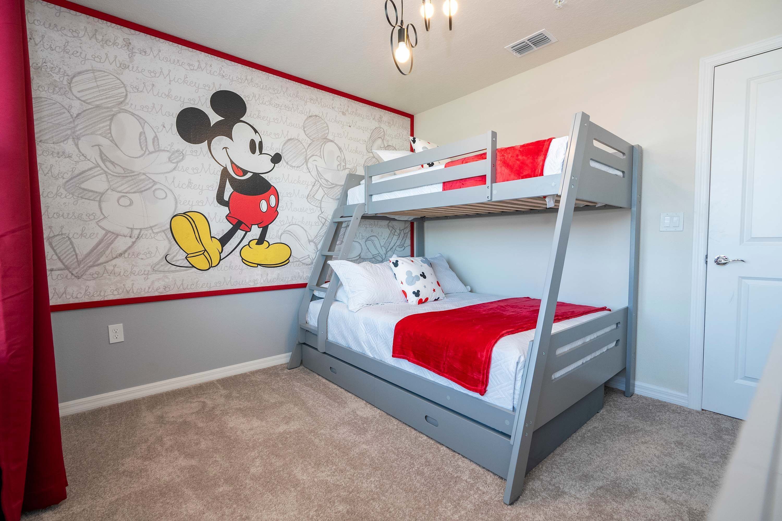 A child's bedroom with a bunk bed, a Mickey Mouse mural, and a red curtain.