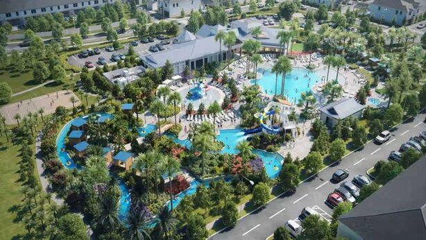 An aerial view of a resort with multiple swimming pools, palm trees, and a parking area.