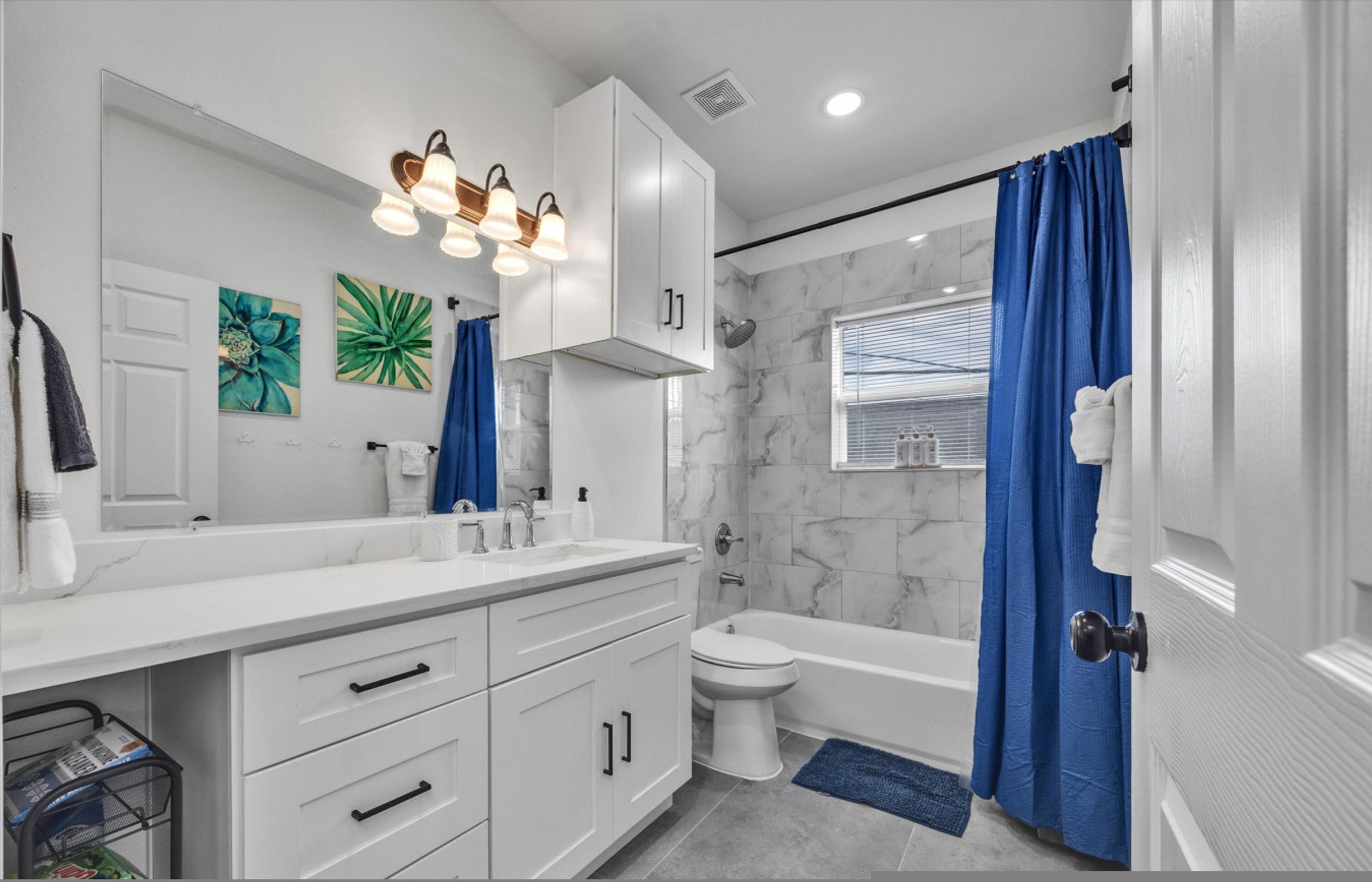 A modern bathroom with a white vanity, a toilet, and a bathtub.