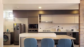 A modern kitchen with a central island, two bar stools, a built-in microwave, and a stainless steel refrigerator. - w Elegant 2BR w Amazing Deco in Medellin (Medellín)