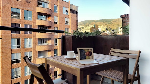 A balcony with a wooden table, chairs, a white cup, and a framed picture. - w Elegant 2BR w Amazing Deco in Medellin (Medellín)