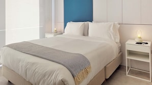 A modern bedroom with a large bed, white bedding, a blue accent wall, and bedside lamps. - w Elegant 2BR w Amazing Deco in Medellin (Medellín)